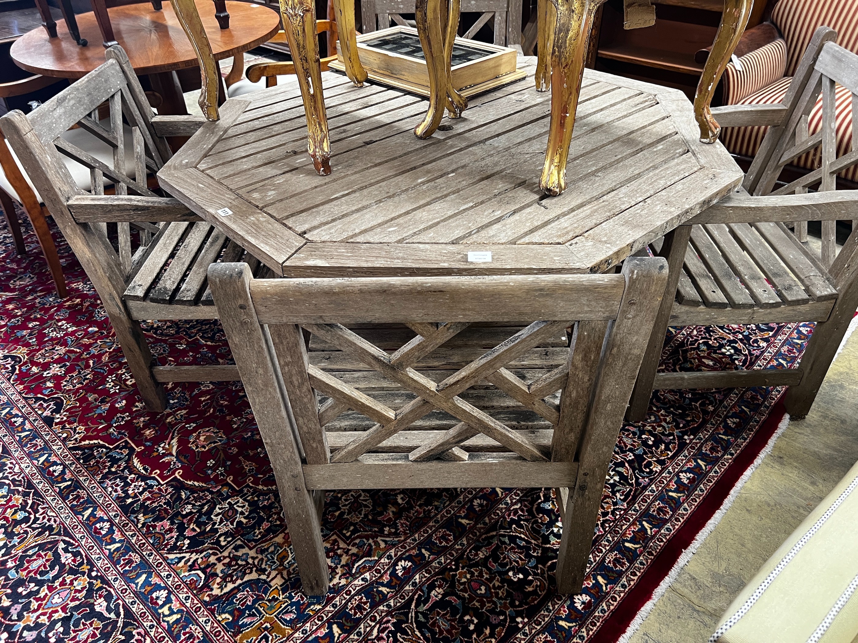 An octagonal weathered teak garden table, length 126cm, height 69cm and four teak elbow chairs